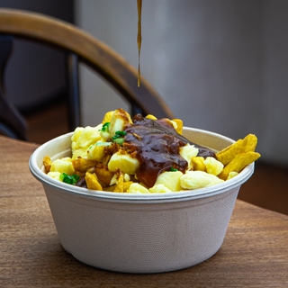 Canadian Poutine dripping into a bowl of fries